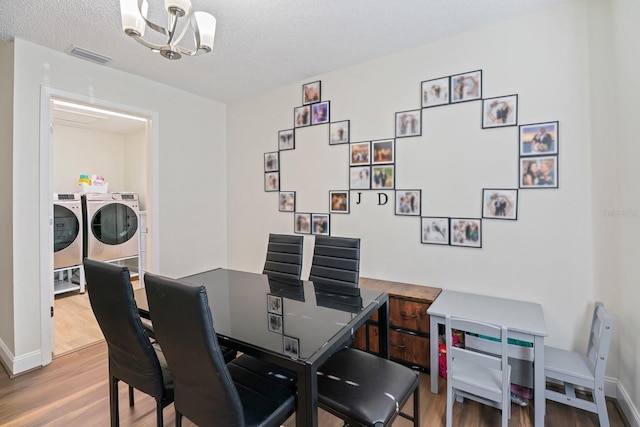 dining area with hardwood / wood-style flooring, independent washer and dryer, an inviting chandelier, and a textured ceiling