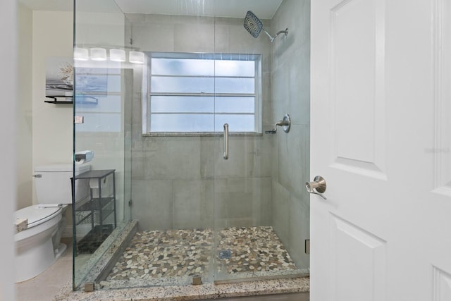 bathroom featuring a shower with door and toilet