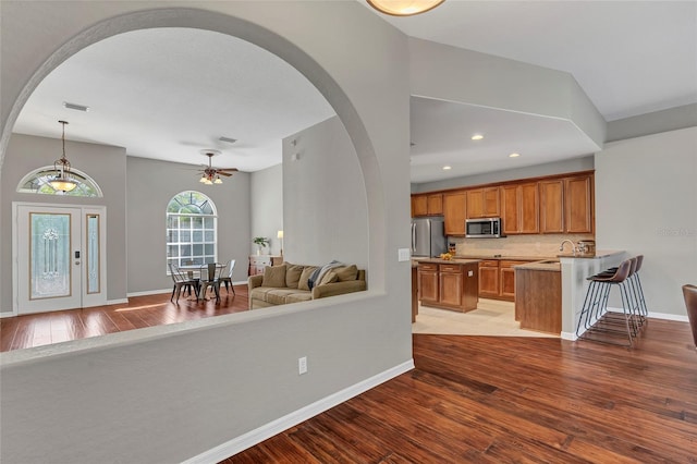 kitchen with hanging light fixtures, stainless steel appliances, sink, and light wood-type flooring