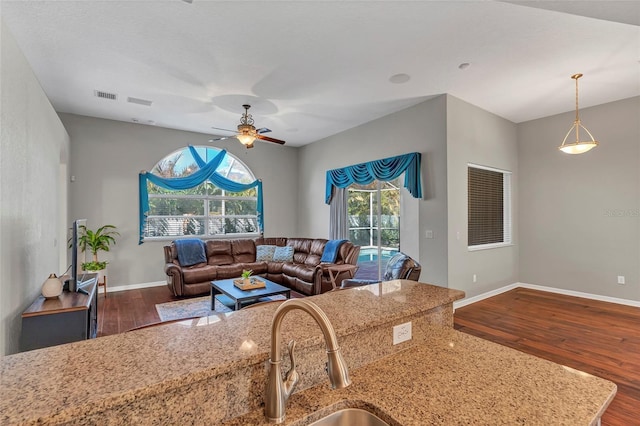 kitchen featuring hanging light fixtures, dark wood-type flooring, light stone countertops, and ceiling fan