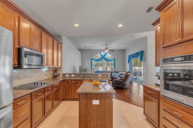 kitchen featuring light stone counters, stainless steel appliances, a kitchen island, and light tile patterned floors