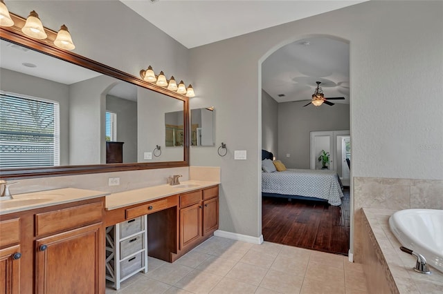 bathroom with ceiling fan, tile patterned floors, tiled bath, and vanity