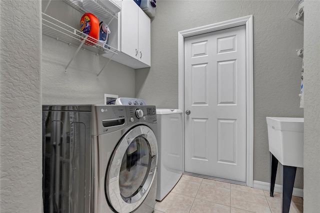 laundry room with cabinets, light tile patterned flooring, and separate washer and dryer