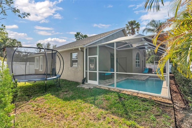 back of property featuring a lawn and glass enclosure