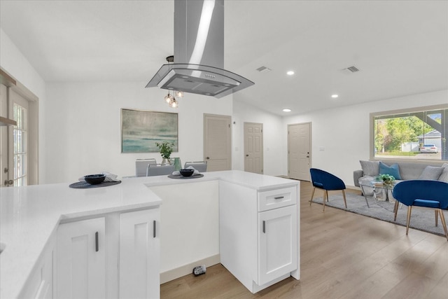 kitchen featuring white cabinetry, island range hood, vaulted ceiling, and light hardwood / wood-style floors