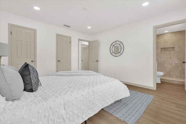 bedroom featuring connected bathroom and light hardwood / wood-style flooring