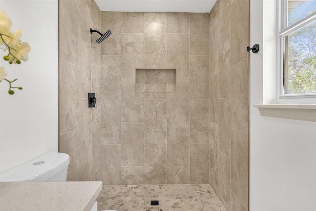 bathroom featuring vanity, toilet, and a tile shower