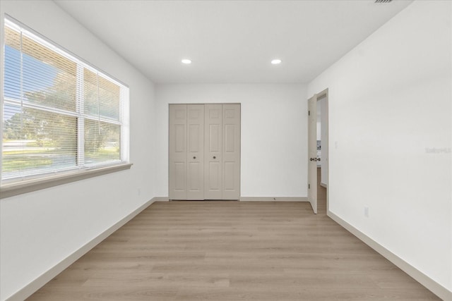 unfurnished bedroom with a closet and light hardwood / wood-style flooring