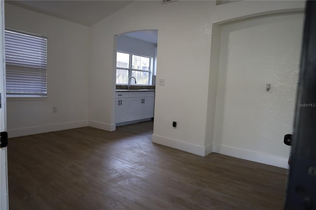 spare room featuring vaulted ceiling, wood finished floors, baseboards, and arched walkways