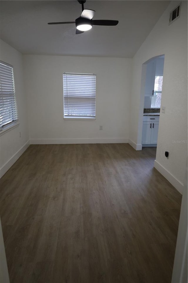 interior space featuring arched walkways, visible vents, a ceiling fan, and dark wood-style floors