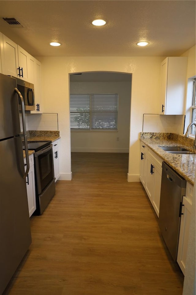 kitchen with a sink, visible vents, appliances with stainless steel finishes, and white cabinetry