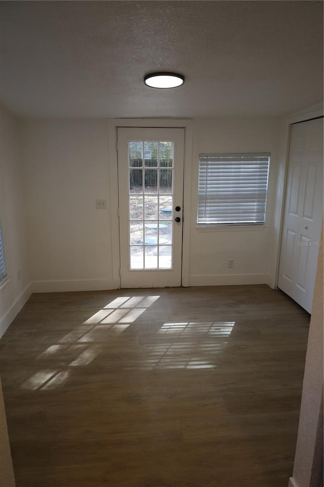 doorway featuring baseboards, a textured ceiling, and wood finished floors