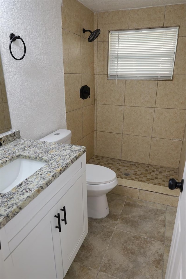 bathroom with vanity, toilet, and tiled shower