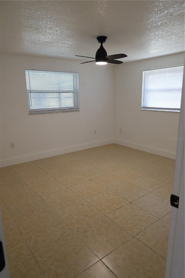 tiled empty room featuring ceiling fan and a textured ceiling