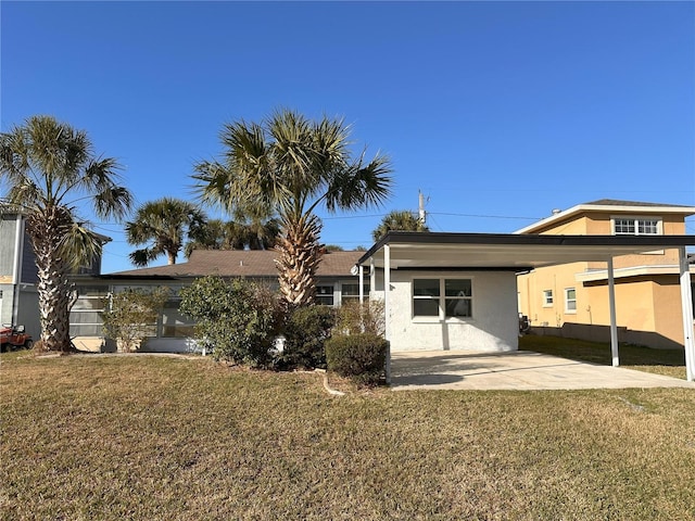 back of property featuring a carport and a lawn