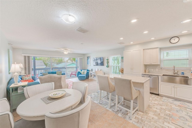 dining space featuring ceiling fan, sink, and a textured ceiling