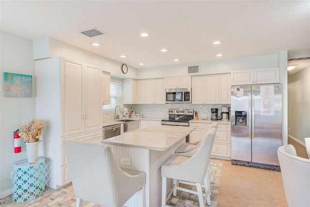 kitchen featuring tasteful backsplash, white cabinetry, appliances with stainless steel finishes, and a center island