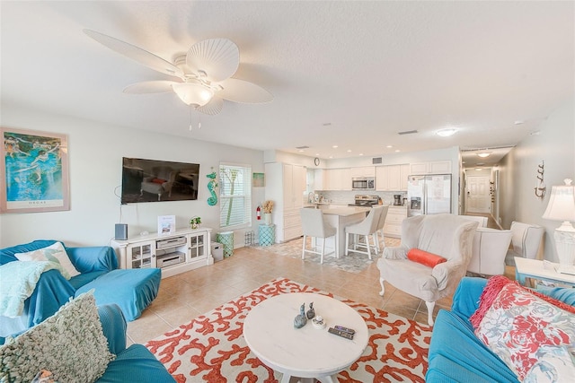 living room featuring light tile patterned floors, ceiling fan, and a textured ceiling