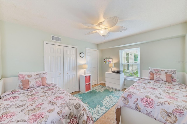 tiled bedroom with ceiling fan and a closet