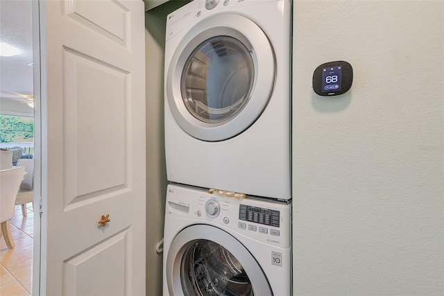 laundry area featuring light tile patterned floors and stacked washing maching and dryer