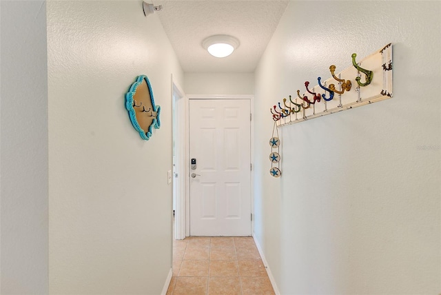 entryway featuring light tile patterned floors, baseboards, and a textured ceiling