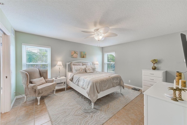 bedroom with ceiling fan, a textured ceiling, and light tile patterned floors