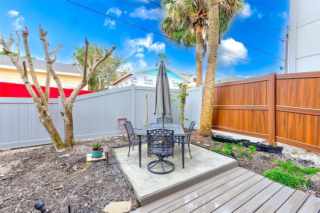 wooden deck with a patio, outdoor dining area, and a fenced backyard