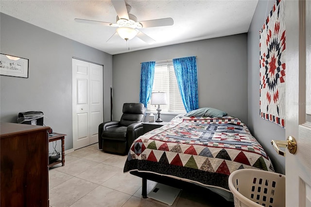 bedroom with ceiling fan, a textured ceiling, a closet, and light tile patterned floors