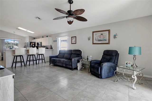 living room with ceiling fan, vaulted ceiling, and light tile patterned floors