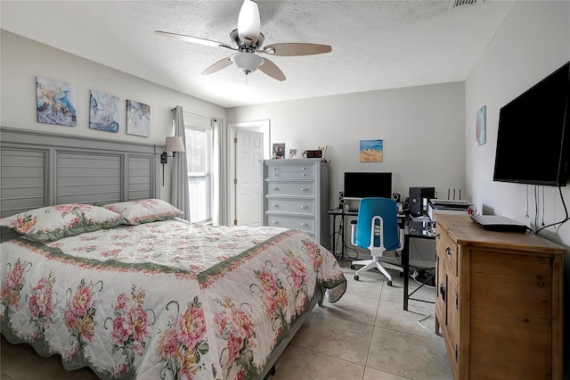 bedroom featuring a ceiling fan, visible vents, light tile patterned flooring, and a textured ceiling