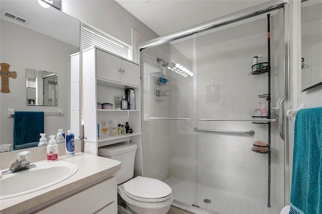 bathroom featuring toilet, a stall shower, visible vents, and vanity