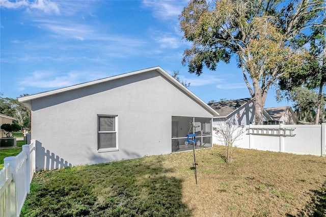 rear view of property featuring a yard, central air condition unit, stucco siding, a sunroom, and a fenced backyard