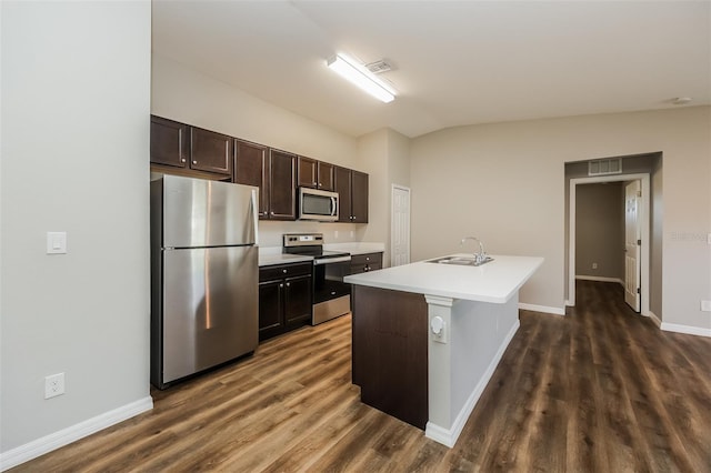 kitchen featuring lofted ceiling, sink, stainless steel appliances, dark brown cabinetry, and a center island with sink