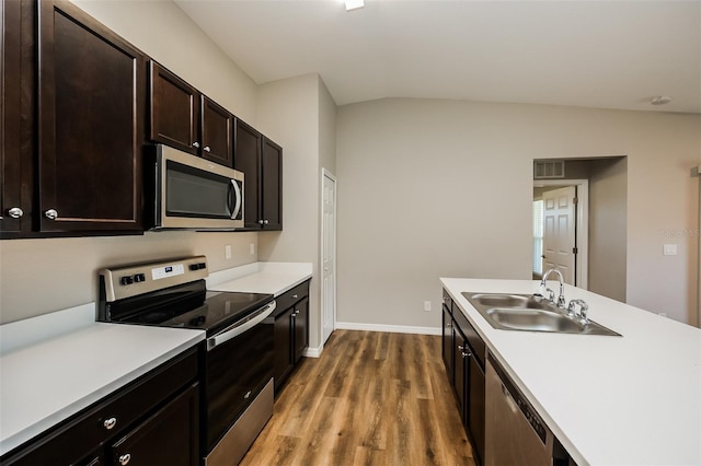 kitchen with sink, vaulted ceiling, dark brown cabinets, stainless steel appliances, and hardwood / wood-style floors