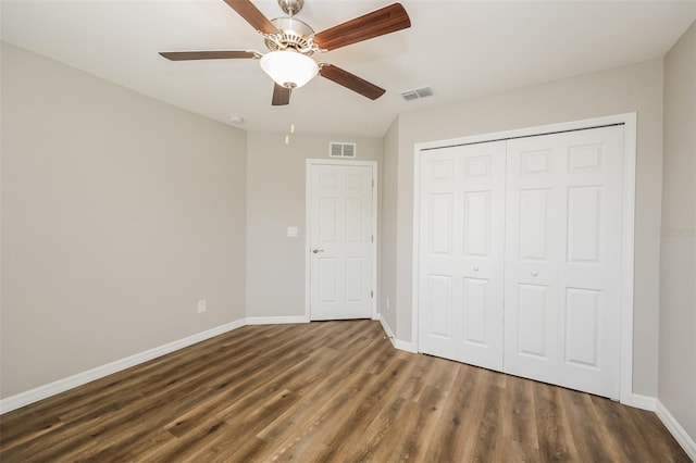 unfurnished bedroom with dark hardwood / wood-style floors, a closet, and ceiling fan