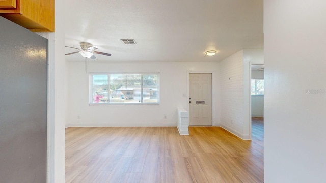 unfurnished room with ceiling fan, brick wall, and light hardwood / wood-style floors