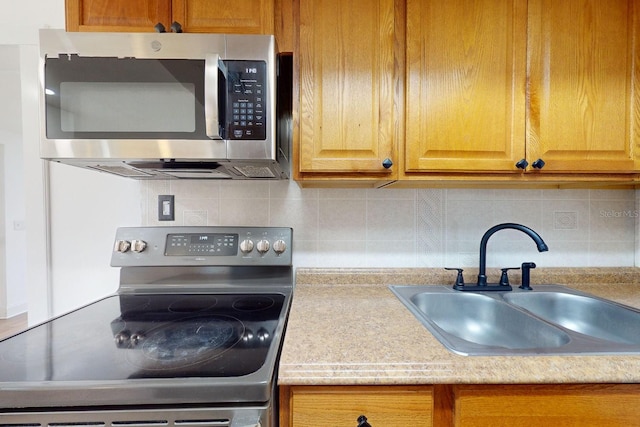 kitchen with appliances with stainless steel finishes, sink, and decorative backsplash