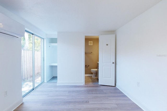 empty room with a wall unit AC and light hardwood / wood-style floors