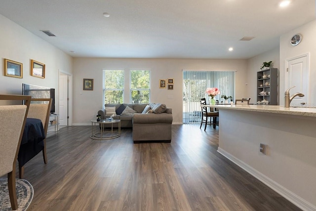 living area featuring dark wood-style floors, visible vents, and baseboards