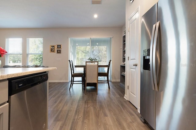 kitchen with visible vents, baseboards, light stone counters, dark wood-style flooring, and stainless steel appliances