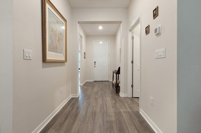 corridor featuring baseboards and dark wood-type flooring