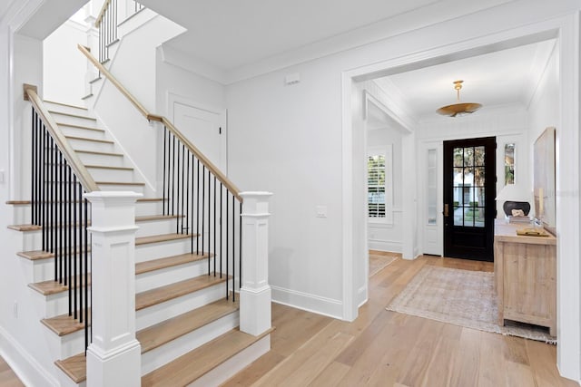 entryway with ornamental molding and light hardwood / wood-style floors