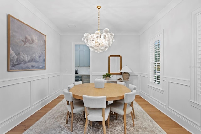 dining space with crown molding, a notable chandelier, and light hardwood / wood-style floors