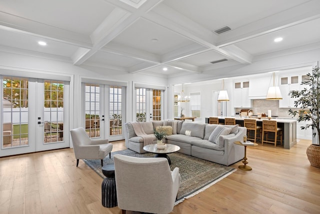 living room with beamed ceiling, coffered ceiling, light hardwood / wood-style floors, and french doors