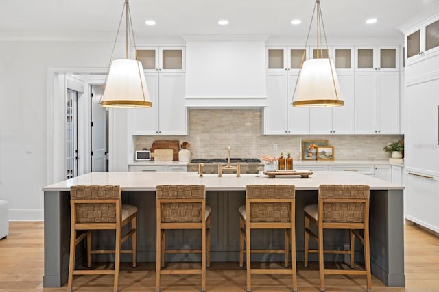 kitchen with a kitchen island with sink, a breakfast bar area, light hardwood / wood-style floors, and tasteful backsplash