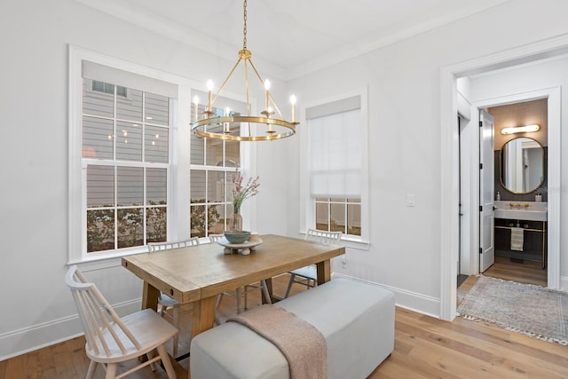 dining area featuring crown molding, a notable chandelier, and light hardwood / wood-style flooring