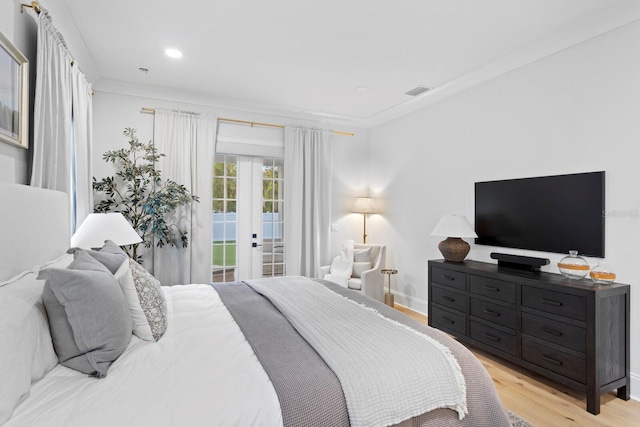 bedroom featuring crown molding, access to outside, light hardwood / wood-style floors, and french doors