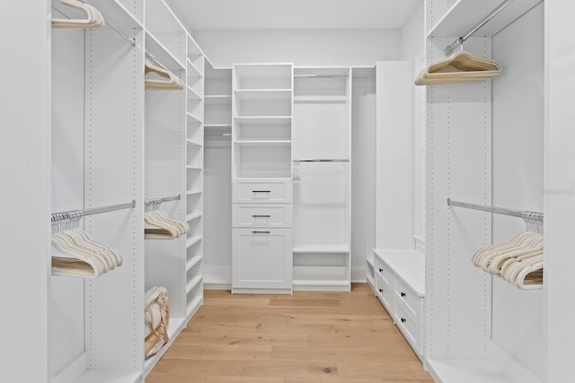 walk in closet with light hardwood / wood-style flooring