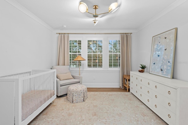 bedroom with crown molding, a nursery area, and light hardwood / wood-style floors