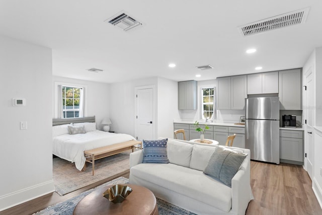 bedroom featuring stainless steel refrigerator, multiple windows, and hardwood / wood-style flooring